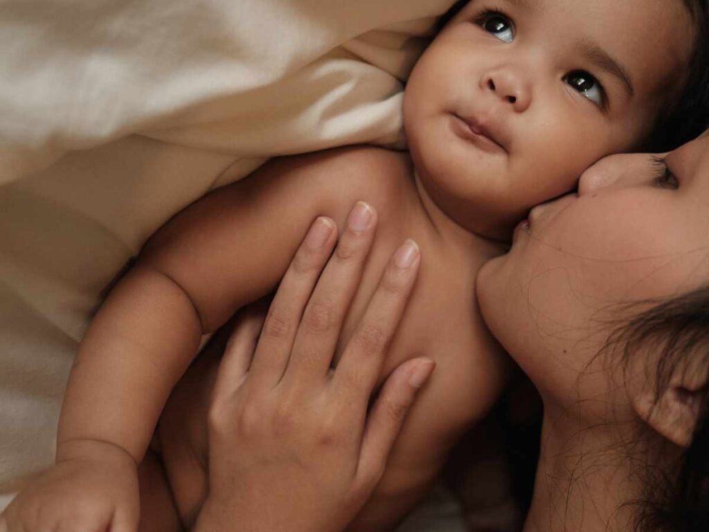 Postpartum mom kissing her baby on the cheek looking happy and peaceful. Get postpartum support for new moms in Ballwin, MO with help from an expert St. Louis therapist here.