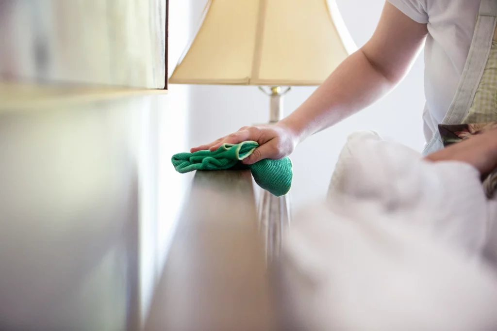 Mother with low grade anxiety cleaning furniture near lamp with rag feeling overwhelmed in St. Louis, MO. Check out maternal mental health counseling st. louis, mo with Marble Wellness. If you're feeling like an overwhelmed mom in missouri we can help you cope with your stressed.