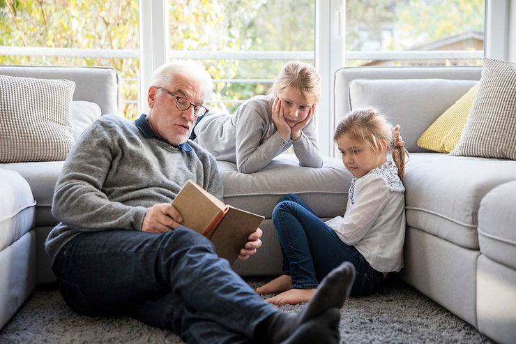 Grandpa reading to two granddaughters. Parenting grieving kids can be tough. Marble Wellness offers grief therapy and also counseling for anxiety, depression therapy, counseling for moms, and more. We offer in-person counseling in West County and telehealth to all residents of Missouri. Call today!