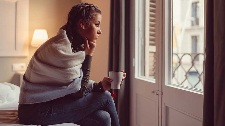 woman alone on her bed looking out the window while she navigates her thoughts while dealing with a divorce. Marble Wellness offers counseling for depression, anxiety, grief, life transitions and much more. Marble Wellness offers in person and virtual therapy sessions .