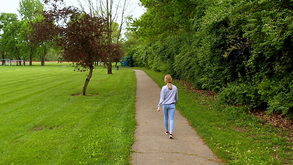 A mother walking alone outside on a walking path at a park. Working moms need time for themselves and talking a walk can help. Marble Wellness is located in Chicago, IL and specializes in working with overwhelmed mothers.