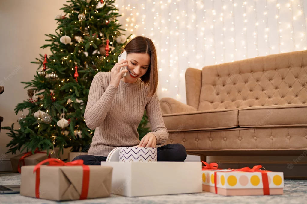 A woman talking to a long distant friend while wrapping gifts for the holiday. Multi-tasking can alleviate stress. Marble Wellness offers therapy for anxiety, depression, life transitions, grief and much more!