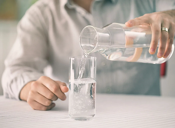 A man pouring himself a glass of water to improve his mood. He is feeling anxiety and is seeking Counseling for Anxiety in St. Louis, MO. Marble Wellness is located in West County, MO 63011 and specializes in anxiety and much more.