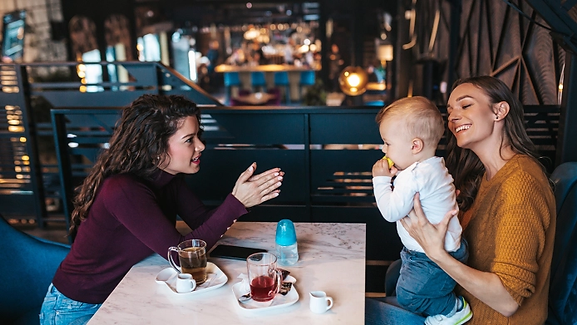 A mother at lunch with her friend. The mother has her baby with her and her friend does not have any kids. The mother is feeling like they are in separate worlds. Marble Wellness is located in Chicago and specializes in working with moms and working moms. 