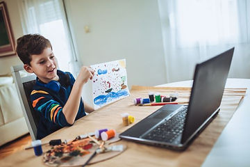 A young child sitting at his kitchen table showing his therapist his artwork through his home computer. He is happy and calm in his own home environment. Marble Wellness offers child therapy for kids in MO and IL!