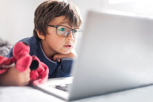 A little boy wearing glasses and holding his fav stuffed animal. He is on a computer doing online child counseling with his therapist. Marble Wellness offers virtual therapy for kids. 