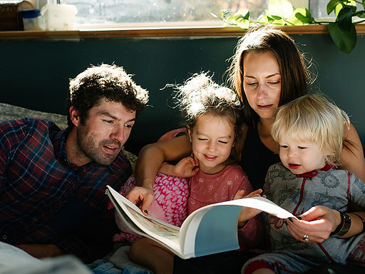 A mother and father having a simple slow down moment of reading  book to their two kids. Seeing the bigger picture and stepping back to enjoy the simpler things is key! Marble Wellness offers therapy to busy moms who need help finding tools and advice on ways to get through the ups and downs of work and motherhood. Marble Wellness if located in Chicago, IL and is taking new clients for in person or virtual sessions. 