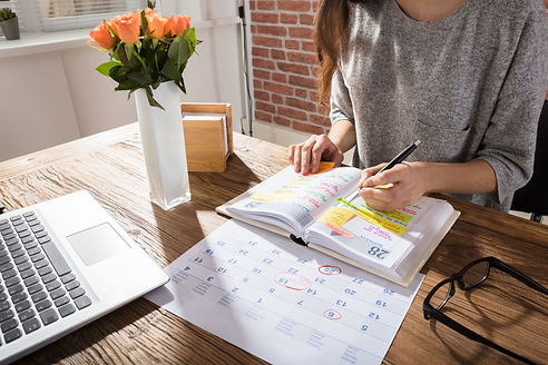 A woman writing on her calendar. Working and busy moms need to make time for self care. Marble Wellness offers counseling services to working Chicago moms who are feeling overwhelmed. Marble Wellness is located in Chicago and has open sessions as soon as next week!