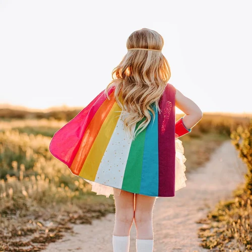 A girl walks on a trail while wearing a superhero cape. Child therapists can help children cope with anxiety, depression, grief, and life transitions. Marble Wellness offers therapy for kids.
