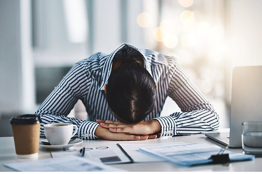 A woman at work with her head down on her desk. The woman is stressed and burnt-out. Marble Wellness specializes in helping women who are experiencing work burn-out. Marble Wellness is located in Chicago, IL can can see clients in person or virtually. 