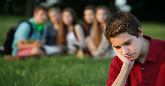 A young adult male sitting outside near classmates but not feeling included. The young man has Chronic Illness and has found that his friends have pulled away from him. Marble Wellness specializes in Chronic Illness and Chronic Pain and can help restore mental health struggles due to illness. 