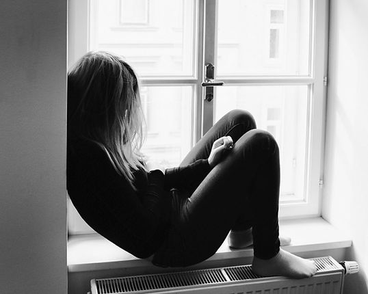 A young adult woman sitting alone in pain. Marble Wellness specializes in therapy for chronic pain. Marble Wellness is located in St. Louis, MO and offers in person or virtual sessions.
