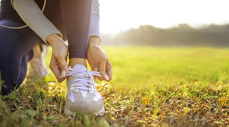 A woman putting on her shoes ready for a walk. Marble Wellness encourages getting outdoors and taking care of yourself. Marble Wellness specializes in maternal mental health, anxiety, depression, postpartum and more. 