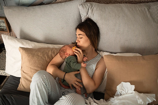 A new mother in bed with her crying baby. She appears exhausted. Marble Wellness specializes in maternal mental health, postpartum depression, postpartum anxiety and overwhelm. 
