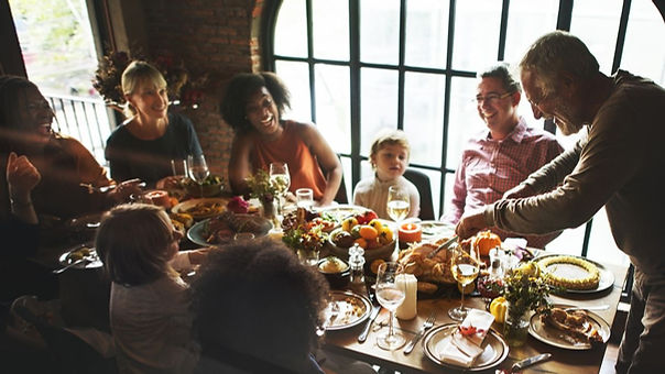 A group of family members gathered at the table for the holiday cutting turkey and looking very happy. Marble Wellness can help mend relationships and help you in dealing with life challenges. 