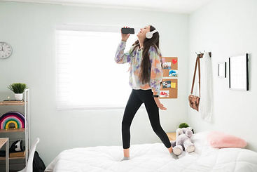 A teen girl on her bed listening to music and dancing. Marble Wellness offers Teen Counseling both in person or virtually.