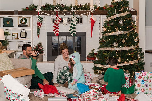 A family of four on Christmas morning opening gifts and smiling. Marble Wellness is a mental health practice specializing in Anxiety, Depression, Maternal Mental Health, Couples Counseling, Teen therapy, Kid therapy and more!