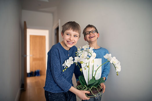 Two boys hold flowers for their mom. Therapy is a great way for moms to care for themselves. Our therapists in St. Louis specialize in maternal mental health.