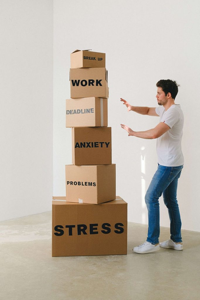 A man deals with a stack of boxes that have different words related to anxiety on them. Overcome anxiety by connecting with an Anxiety Therapist in St. Louis, MO today.