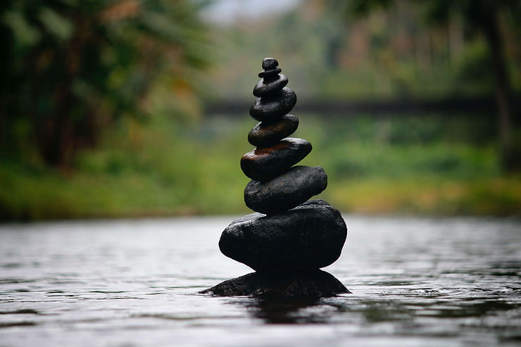 A stack of black rocks surrounded by water. Learn tips and tricks to create a zen space of your own in Therapy for Anxiety in St. Louis, MO.