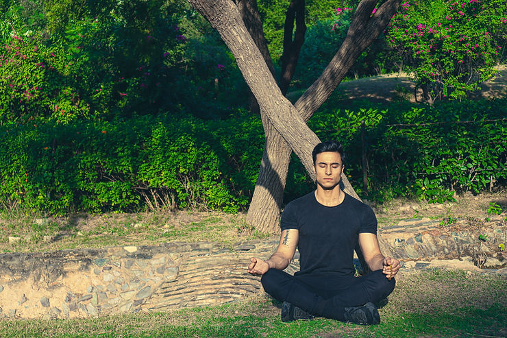 A man meditates outside on a sunny day. Learn to implement mindfulness in your daily life in Therapy for Anxiety in St. Louis, MO. 