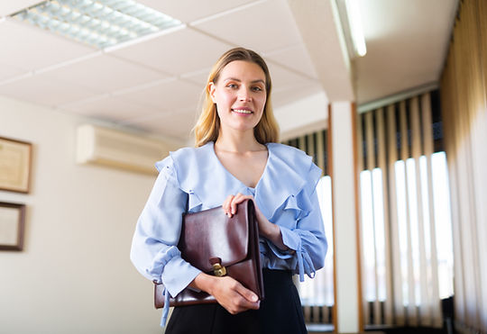 A woman holds a briefcase in her office. Marble Wellness specializes in therapy for moms in Missouri and Illinois through in-person therapy, virtual therapy, and park therapy.