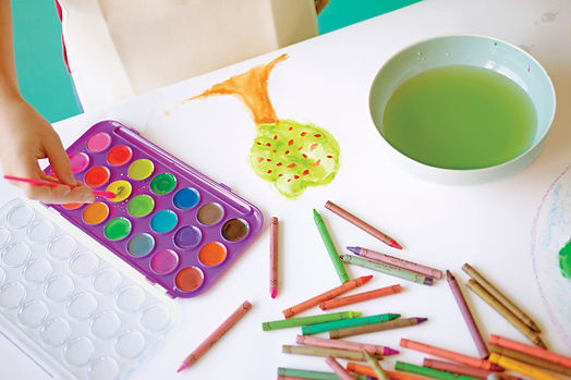 A child uses watercolors to paint a tree. Play therapy is offered by Marble Wellness in St. Louis, MO 63011.