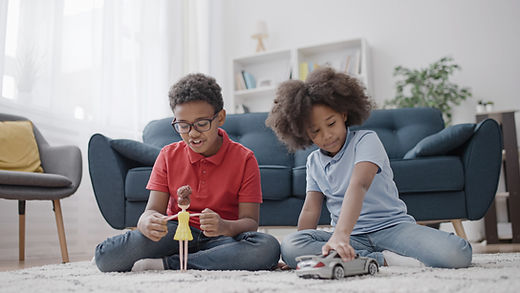 A brother and sister play with a toy car and a doll. Play therapy for kids is offered by Marble Wellness in Ballwin, MO 63011.