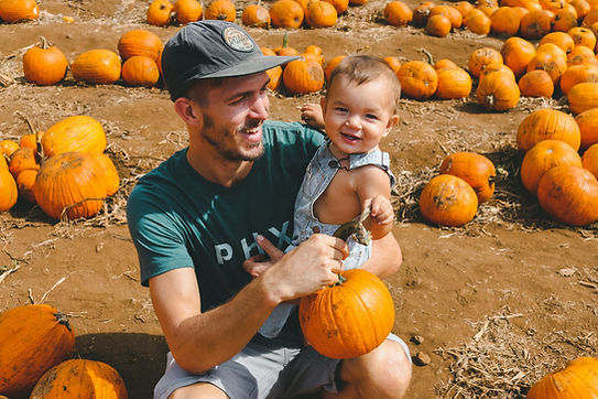 A dad holds his baby at a pumpkin patch. Marble Wellness has a male therapist in St. Louis, MO who specializes in counseling for men, teen therapy, family therapy, and couples counseling. 