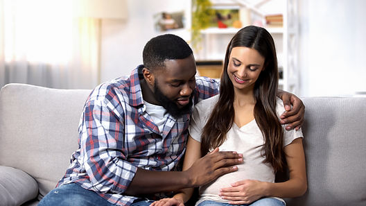 A man touches the belly of his pregnant female partner. Dads can find mental health support through therapy at Marble Wellness in Ballwin, MO 63011, which specializes in men's mental health and offers therapy for men.