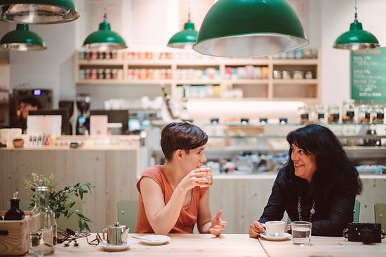 Two women drink coffee in a cafe. Women can benefit from life transition therapy at Marble Wellness in St. Louis, MO, where they can find a therapist near me. In-person therapy, online therapy, and park therapy are offered in Ballwin.