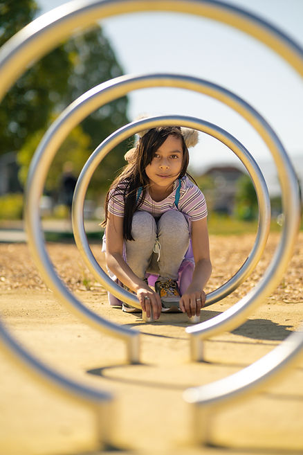 A young girl plays on a playground. Therapy in West County, Missouri can help families thrive. Family therapists in St. Louis are available at Marble Wellness for in-person therapy, online therapy in Missouri, online therapy in Illinois, and park therapy.