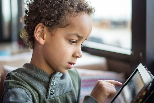 A boy reads his tablet. St. Louis child therapists at Marble Wellness offer in-person child therapy in Ballwin, MO, online child therapy in Missouri, and park therapy at Queeny Park in West County, MO.