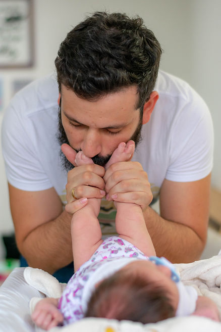 A dad kisses his baby's feet. St. Louis therapist Skyler Martin offers therapy for men in St. Louis at Marble Wellness. Marble Wellness also specializes in therapy for moms, child therapy, teen therapy, couples therapy, grief therapy, and family therapy.