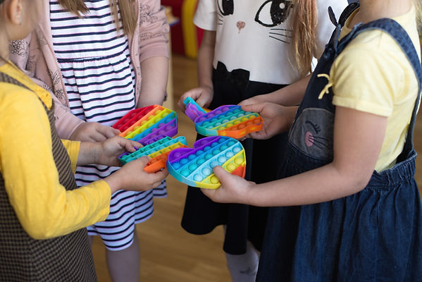 Girls play with fidget toys at school. Play therapy techniques are used in child therapy in St. Louis at Marble Wellness. Family therapy is also available, as well as couples counseling in West County, MO.
