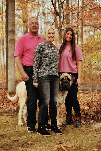 A mom, dad, daughter, and dog stand together in the woods. Family therapy in St. Louis is available in-person in Ballwin, online therapy in Missouri, online therapy in Illinois, and park therapy in Queeny Park in St. Louis County are all offered by Marble Wellness.