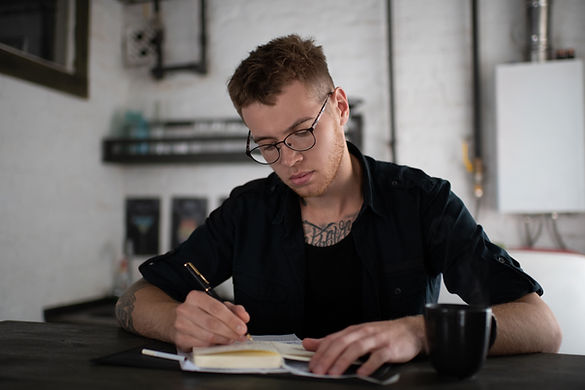 A teenage boy writes in a notebook at a desk. Marble Wellness therapist Skyler Martin specializes in family therapy, therapy for teenagers, and substance abuse counseling in St. Louis, MO.