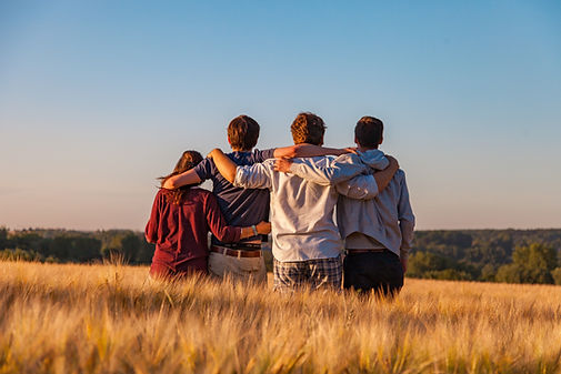A mom, dad, and two sons with their arms around each others' shoulders look across a field. Marble Wellness, a therapy practice in West County, MO, offers family therapy in St. Louis, teen therapy, play therapy, and couples counseling.