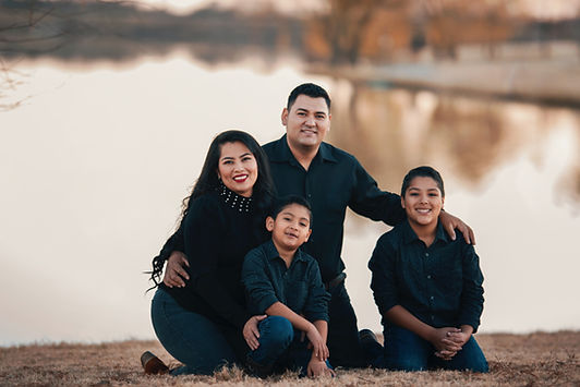 A mom, dad, and two children sit together in front of a lake. Family therapy in St. Louis is available at Marble Wellness, a mental health counseling practice in West County, MO.
