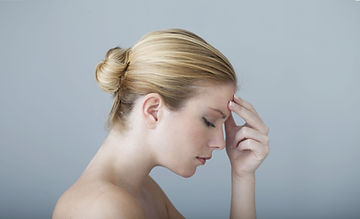 Woman holding head; racing thoughts can be a reason to start anxiety counseling. So can constant headaches, which are usually a somatic symptom of untreated anxiety.