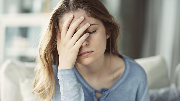 A woman holding her forehead looking exhausted from her anxiety. She has her eyes closed and seems to be overwhelmed. Marble Wellness offers Anxiety Counseling in Missouri. 