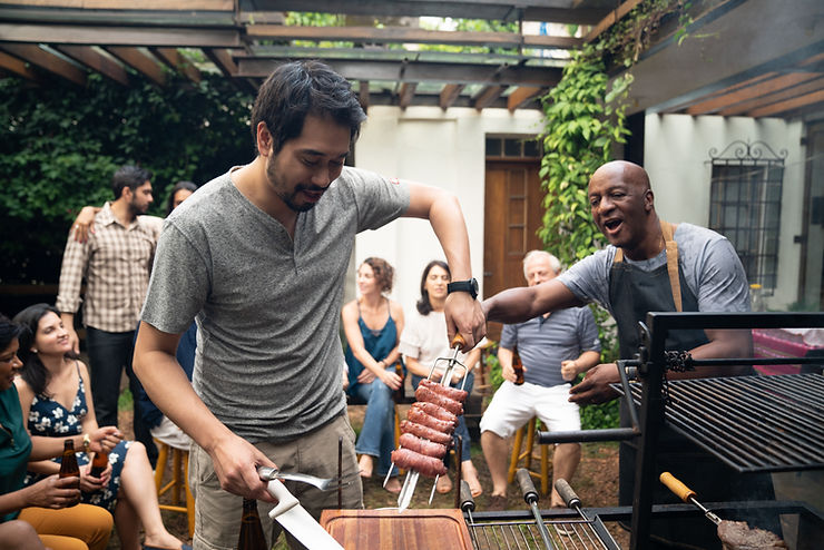 Two men grilling at a party with other adults behind them enjoying the cookout. Making friends as an adult is hard. Follow these tips to help change your mindset about making new friends and gaining some traction on increasing your social satisfaction! Marble Wellness is here for you if you are experiencing anxiety, depression, grief, maternal overwhelm in St. Louis!