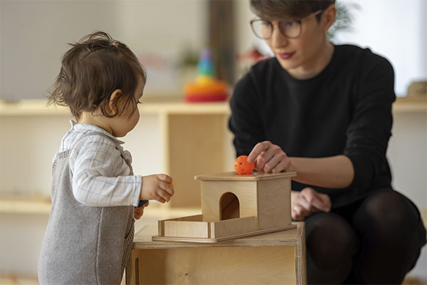 Photo of a therapist and a child doing an exercise with a wooden toy while in therapy. Happy after Play Therapy | Play Therapy in St. Louis, MO 63011.