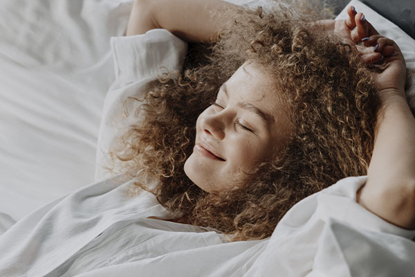 Photo of a woman lying on a bed smiling. There is hope to feel better after anxiety treatment in St. Louis, MO 63011. Marble Wellness can provide counseling for anxiety. We offer in-person sessions, telehealth in Missouri, and park therapy too!