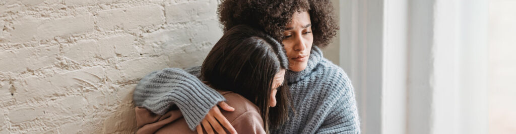 Photo of a woman hugging and supporting other women. You can feel peace after getting grief therapy in West County, MO. You can get help with the grieving process in online therapy in Missouri. Marble Wellness also offers grief counseling in-person in St. Louis, MO. 
