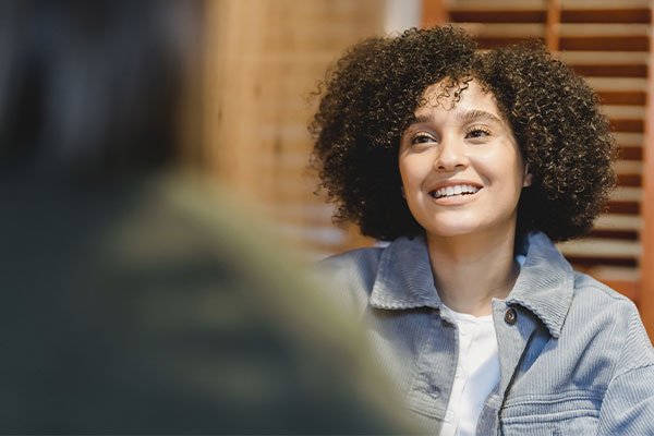 Photo of a woman smiling while talking to another person right before her while having in-person therapy in Chicago, IL. You can feel better and talk to a therapist in-person in Chicago in Marble Wellness.