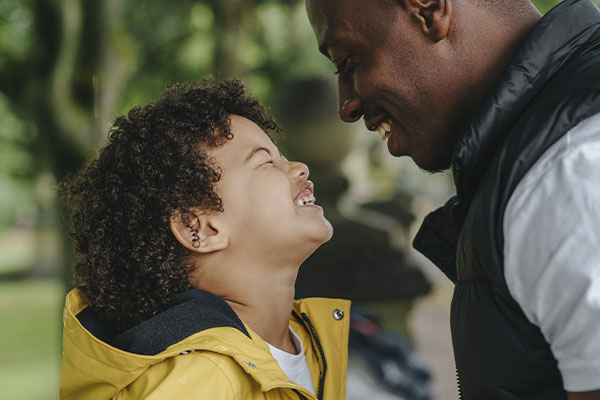Photo of a happy man smiling and looking to his son after therapy for men in St. Louis, MO with Marble Wellness. You can get help with online therapy in Missouri and counseling for men in STL. Find relief today with online counseling in Missouri.