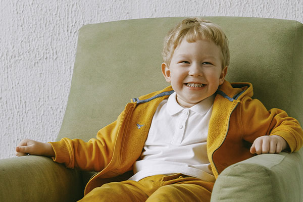 Photo of a happy child sitting in a green armchair. Play therapy can bring relief to you and your child. Marble Wellness offers Play therapy in St. Louis, MO 63011.