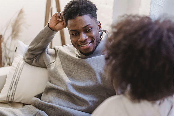 Photo of a man sitting on the couch, slightly smiling at a woman. Breakup recovery in Chicago, IL | therapy for breakups in Chicago, IL | relationship therapy for singles | relationship therapist | 63122 | forrest glen 60630 | Lincoln Park is 60614 | north center 60613 | 60618