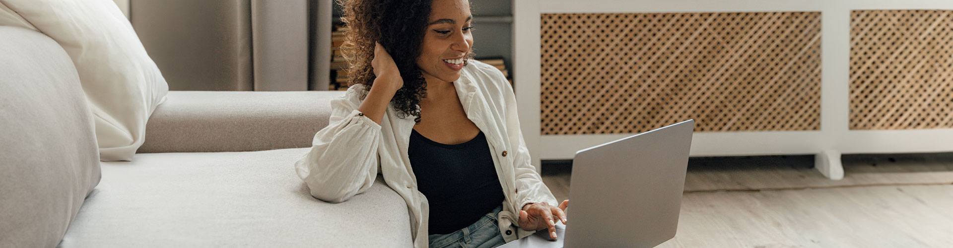 Photo of a woman sitting on the ground at her computer talking and smiling. You can feel better without leaving your house via online therapy in Chicago, IL with Marble Wellness.